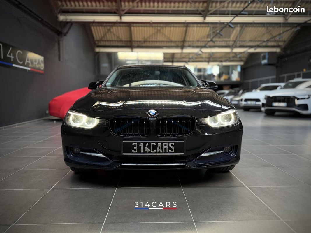BMW Série 3 noire photographiée de face dans le showroom 314CARS